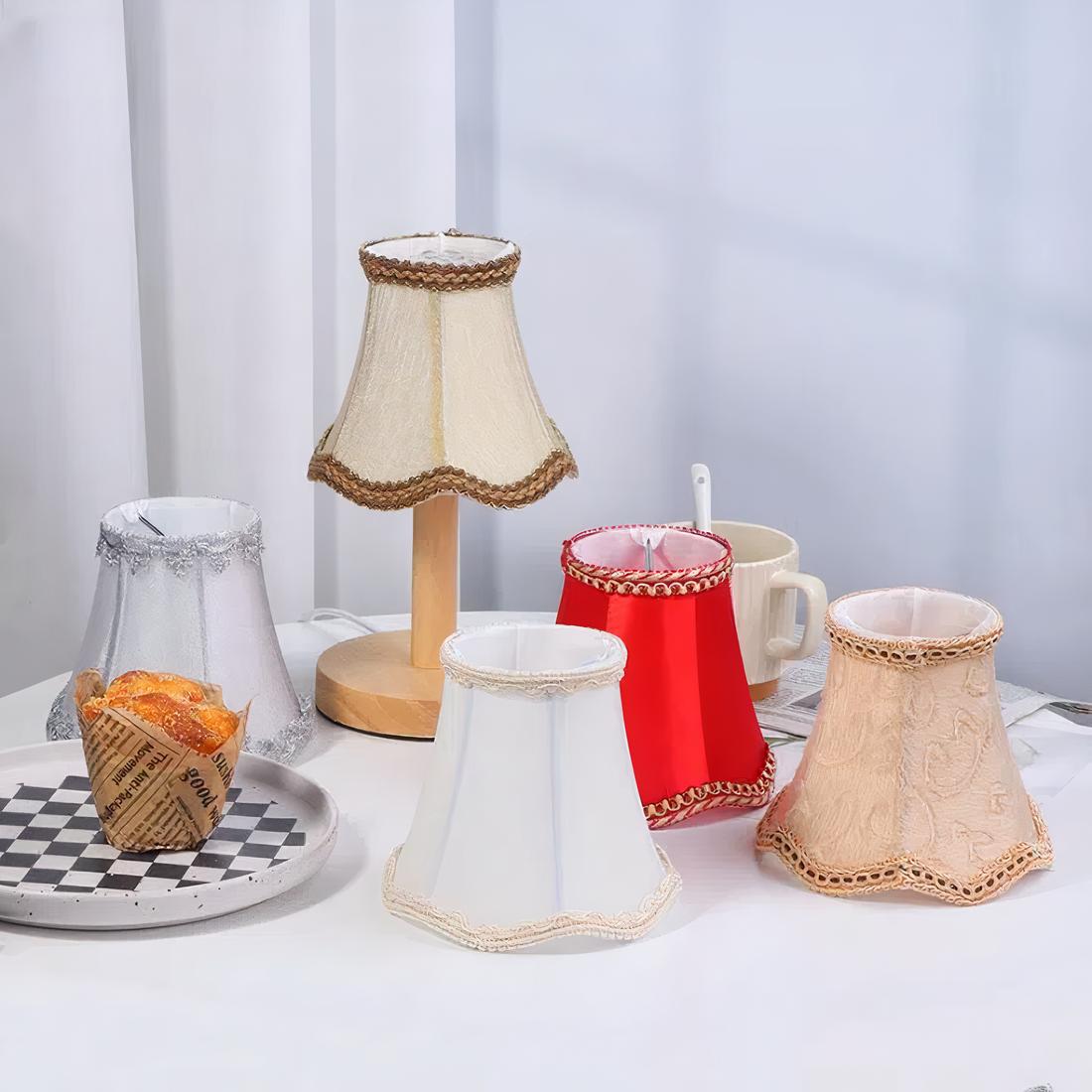 5 abats jours rétro en tissu jacquard de couleurs différentes posés sur une table avec une nappe blanche