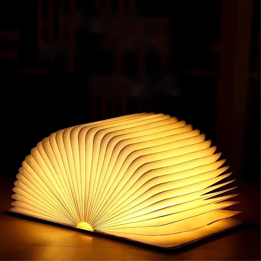 Lampe de chevet rechargeable en forme de livre ouvert. La lumière est diffusée à travers les pages. Sur fond noir.
