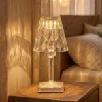 Lampe de chevet effet cristal scintillant rechargeable posée sur table bois, diffuse lumière chaude avec reflets géométriques élégants, créant ambiance cosy près lit.